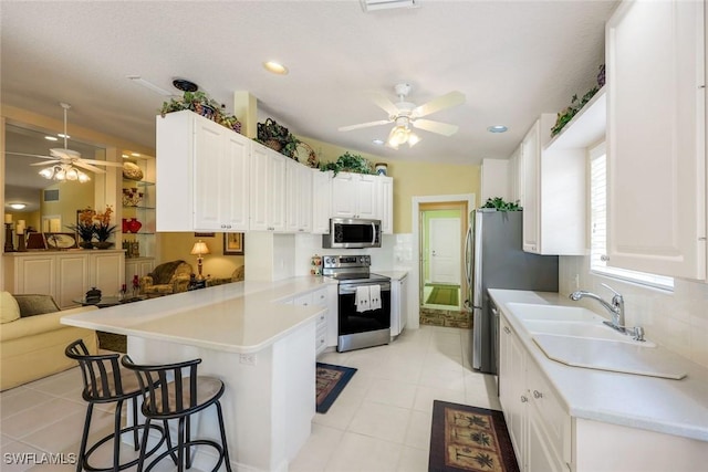 4221 Saint George Ln, Naples, FL 34119 - kitchen with stainless steel appliances, a kitchen bar, a peninsula, and a ceiling fan