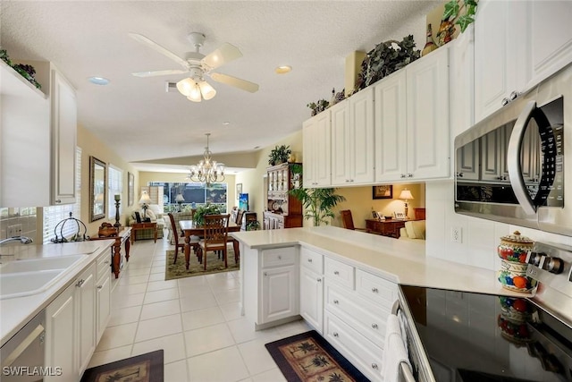 4221 Saint George Ln, Naples, FL 34119 - kitchen with light tile patterned floors, a peninsula, stainless steel appliances, a sink, and white cabinets