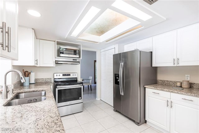 183 Old Tamiami Trl, Naples, FL 34110 - kitchen featuring stainless steel appliances, a sink, exhaust hood, light tile patterned floors, and white cabinetry
