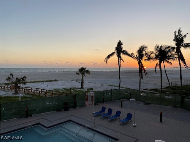 pool at dusk featuring a water view