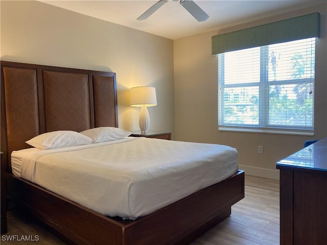 bedroom with a ceiling fan, baseboards, and light wood-type flooring