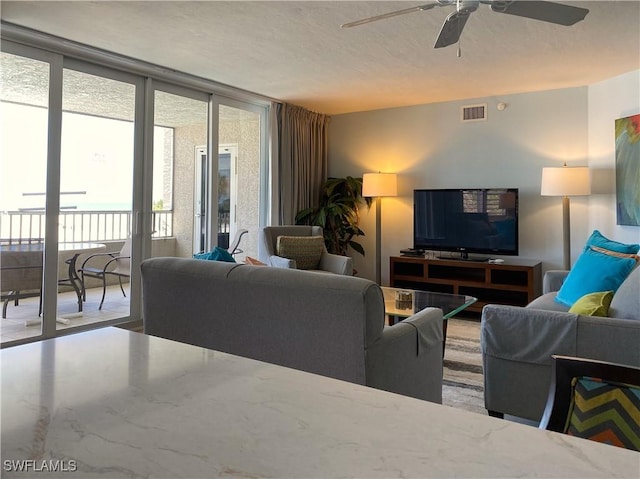 living room featuring a wall of windows, visible vents, and ceiling fan