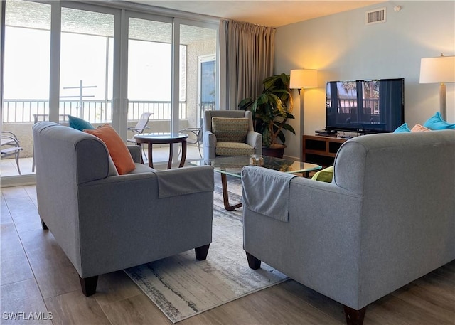 living room featuring wood finished floors, a healthy amount of sunlight, and visible vents