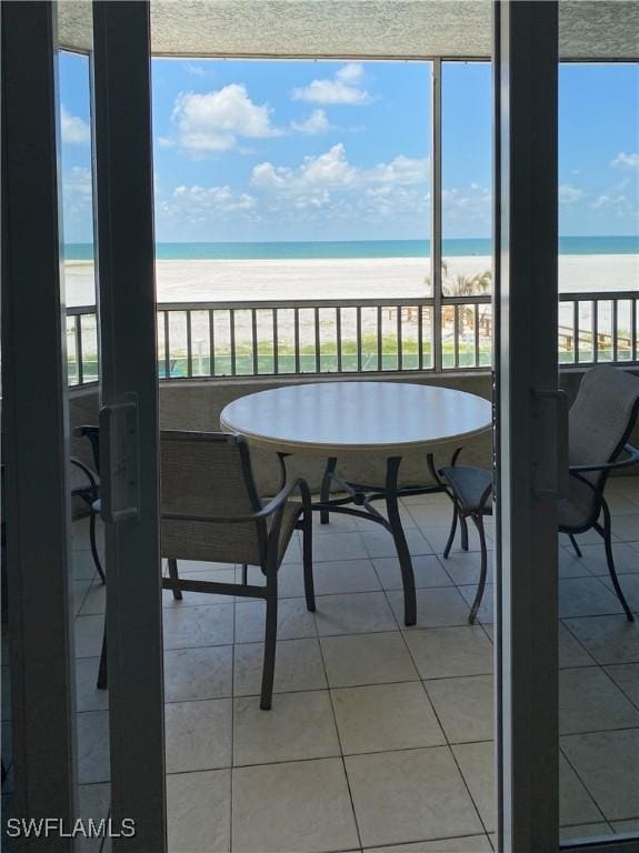 sunroom / solarium featuring a view of the beach, plenty of natural light, and a water view