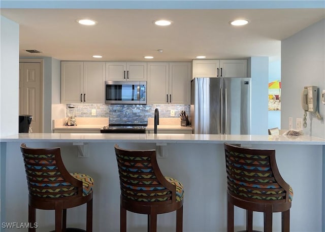 kitchen with decorative backsplash, a peninsula, and stainless steel appliances