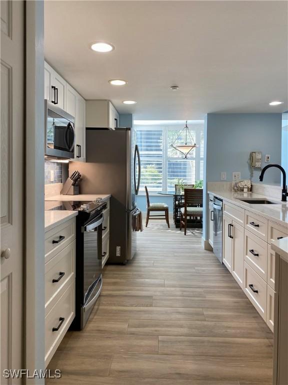 kitchen featuring white cabinets, light wood-style floors, appliances with stainless steel finishes, and a sink