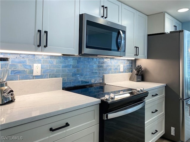 kitchen with light stone countertops, backsplash, appliances with stainless steel finishes, and white cabinets