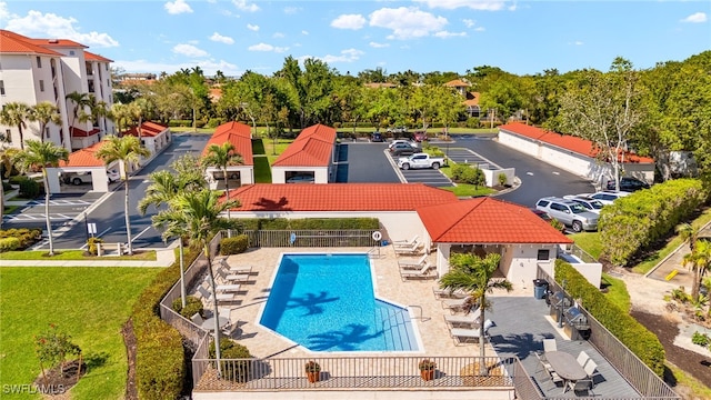 pool with a patio area, a residential view, a yard, and fence