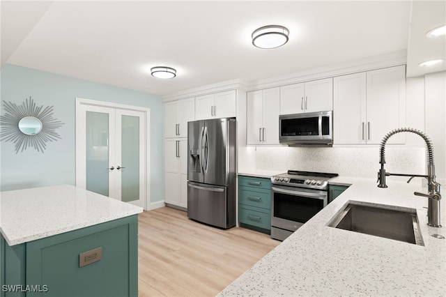 kitchen featuring a sink, light stone counters, white cabinetry, stainless steel appliances, and green cabinetry