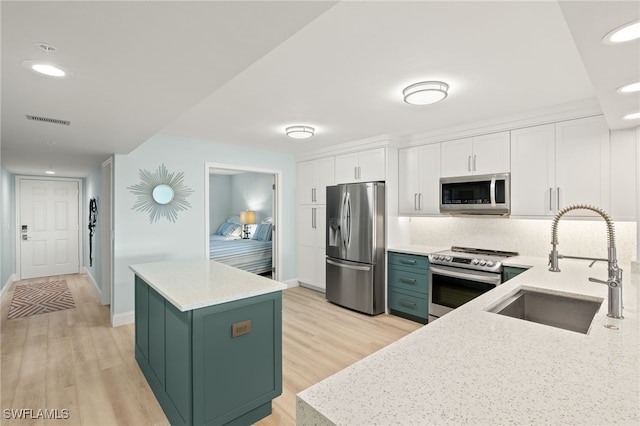 kitchen with visible vents, a sink, white cabinetry, stainless steel appliances, and green cabinetry