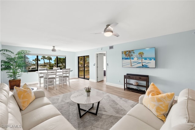 living area with visible vents, baseboards, light wood-type flooring, and ceiling fan