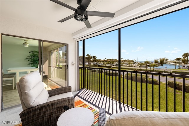 sunroom featuring a water view and a ceiling fan