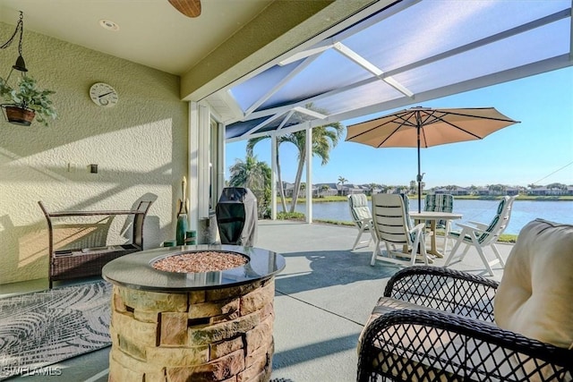 view of patio with glass enclosure, a water view, and grilling area