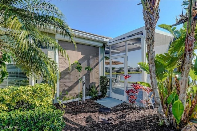 view of side of home with glass enclosure and stucco siding