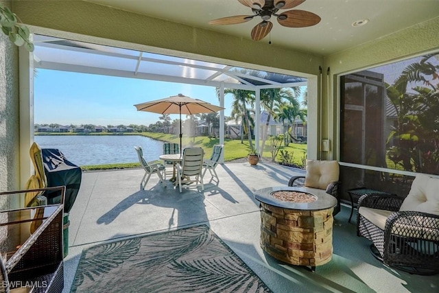 view of patio featuring a lanai, outdoor dining area, a ceiling fan, and a water view