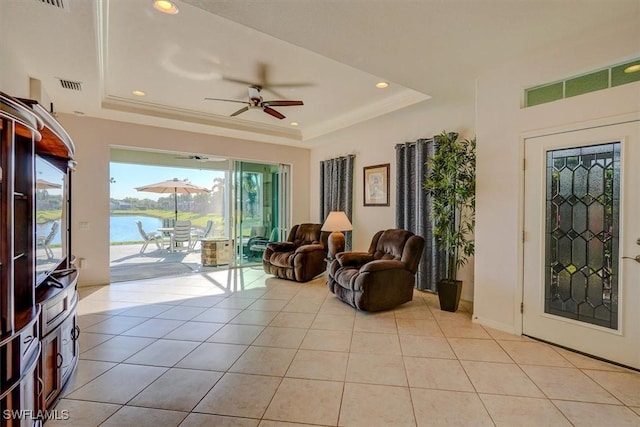 sitting room with a tray ceiling, visible vents, light tile patterned flooring, and a ceiling fan