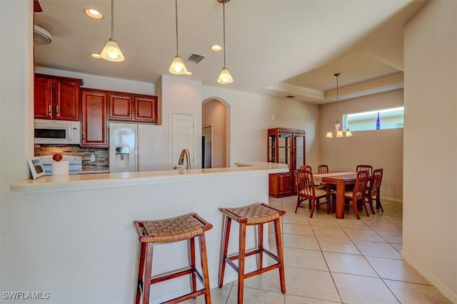 kitchen with visible vents, backsplash, white appliances, arched walkways, and a raised ceiling