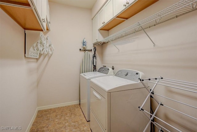 laundry area with baseboards, cabinet space, and washing machine and dryer