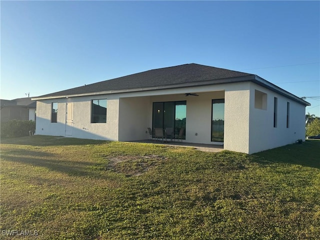 rear view of property featuring stucco siding, a patio, a yard, and a ceiling fan