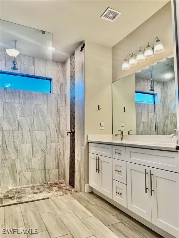 bathroom with visible vents, a walk in shower, and vanity