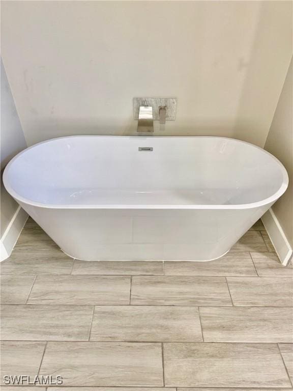 bathroom featuring baseboards and a freestanding bath