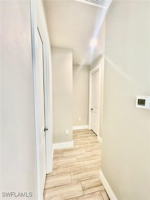 hallway featuring baseboards and wood finish floors