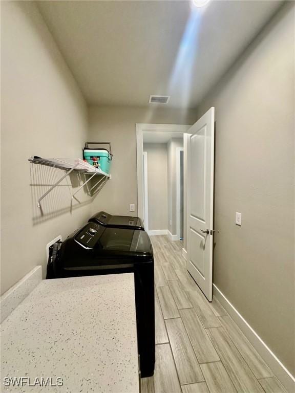 clothes washing area with visible vents, baseboards, wood tiled floor, laundry area, and independent washer and dryer