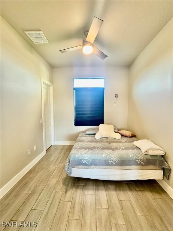 bedroom with visible vents, ceiling fan, baseboards, and wood finish floors