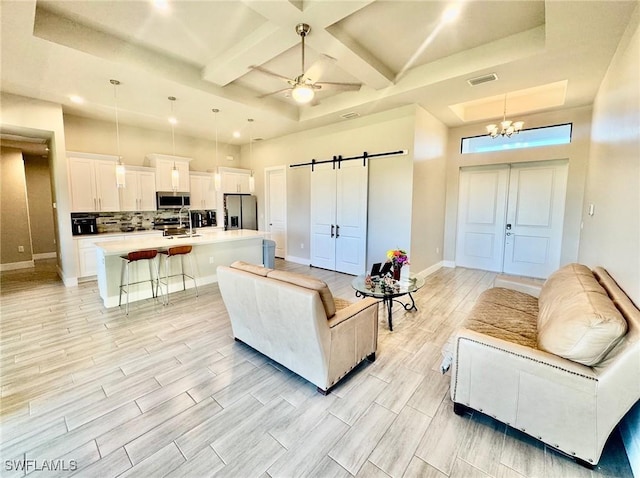 living room with a barn door, visible vents, coffered ceiling, and wood finish floors