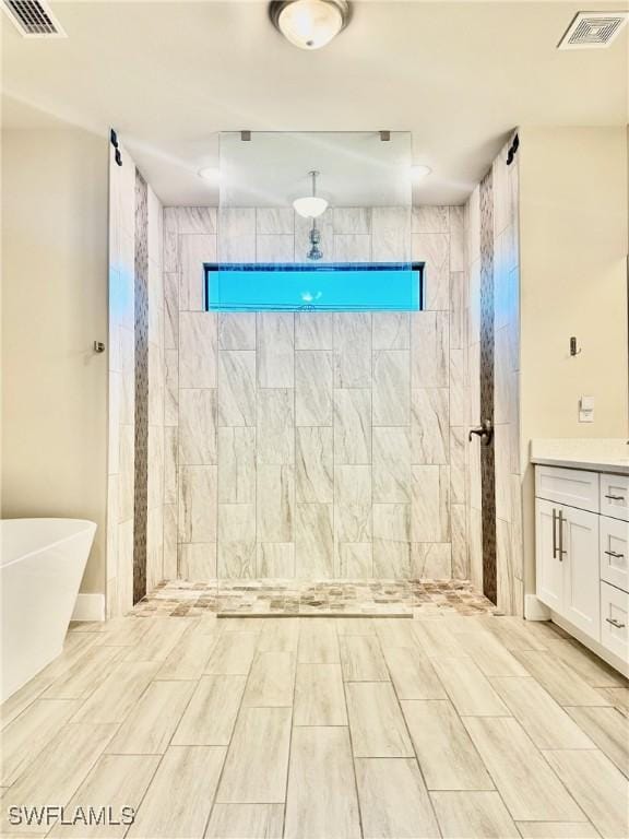 bathroom with visible vents, a freestanding bath, vanity, and a tile shower