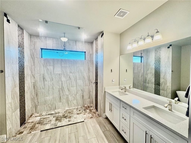 bathroom with double vanity, a walk in shower, visible vents, and a sink