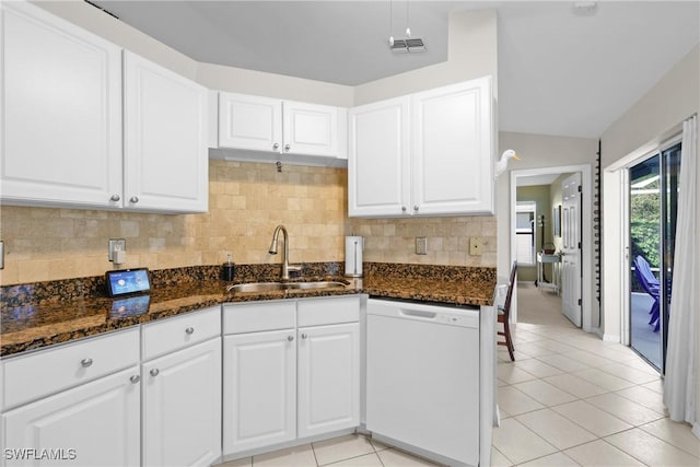 kitchen with dark stone countertops, light tile patterned floors, visible vents, white dishwasher, and a sink