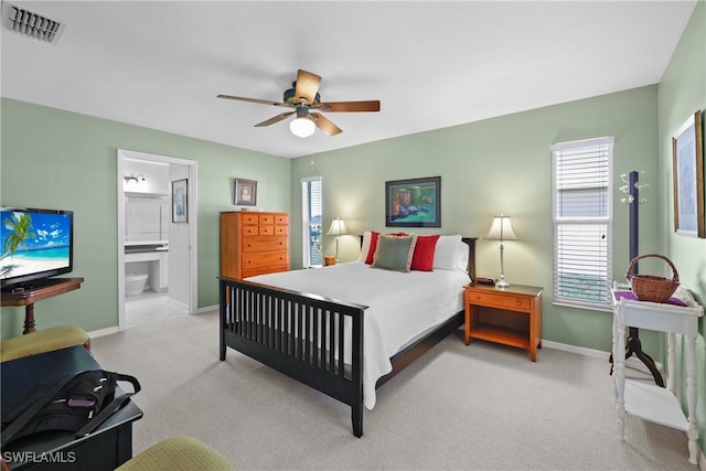 bedroom with visible vents, baseboards, ceiling fan, light colored carpet, and ensuite bathroom