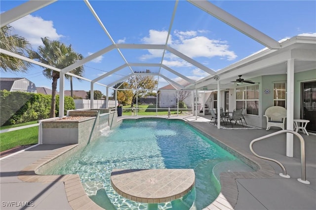 view of pool with fence, glass enclosure, a fenced in pool, ceiling fan, and a patio area