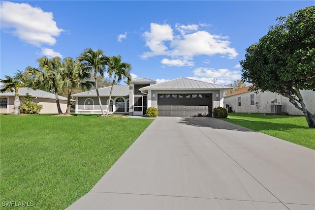 view of front of home featuring a front lawn, central AC, metal roof, driveway, and an attached garage