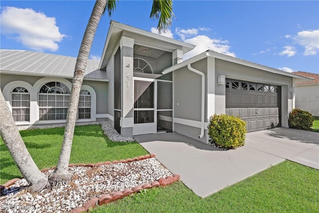 view of front facade featuring a front yard, stucco siding, concrete driveway, a garage, and metal roof