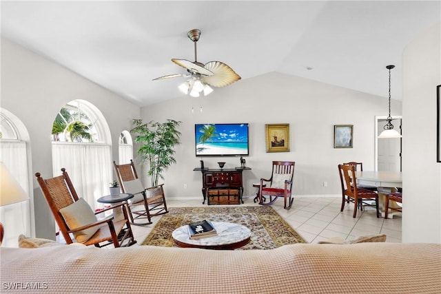 living area featuring tile patterned flooring, baseboards, a ceiling fan, and vaulted ceiling