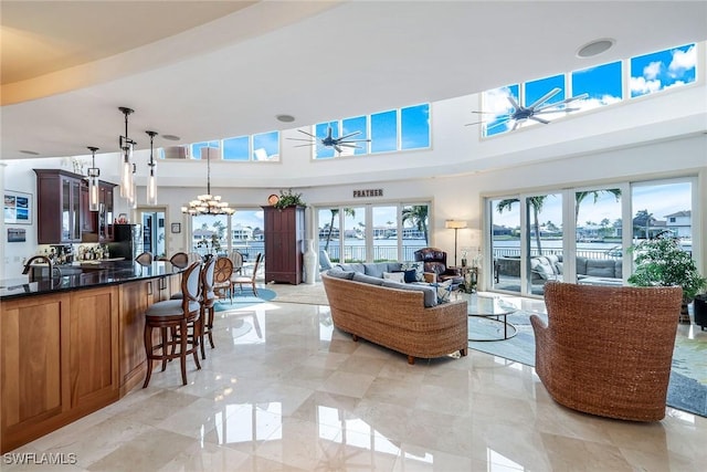 living room featuring ceiling fan with notable chandelier and a towering ceiling