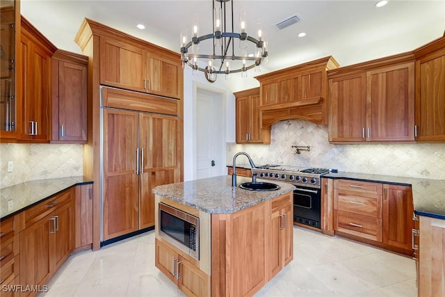 kitchen featuring light stone counters, visible vents, built in appliances, and a sink