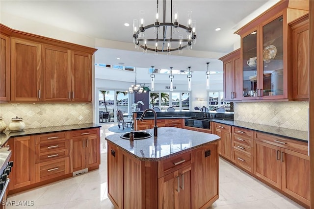 kitchen with dark stone counters, pendant lighting, a chandelier, and brown cabinetry