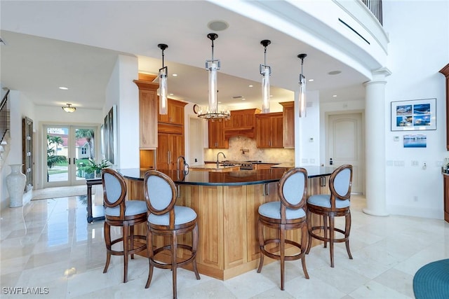 kitchen with decorative columns, french doors, dark countertops, a kitchen breakfast bar, and backsplash