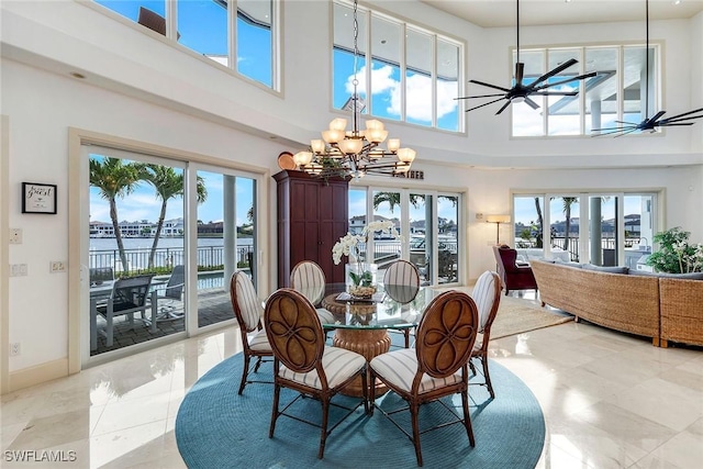 dining room featuring plenty of natural light, ceiling fan with notable chandelier, a high ceiling, and baseboards