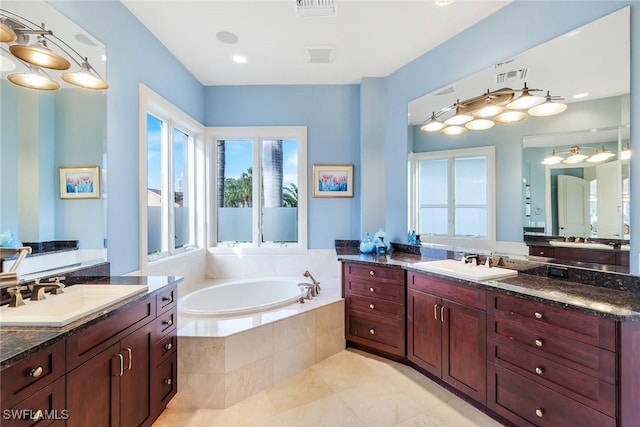 full bath featuring a bath, visible vents, two vanities, and a sink