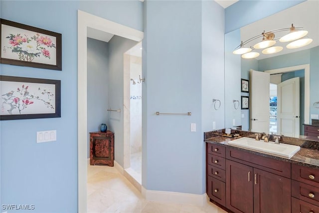 full bathroom with tile patterned floors, baseboards, tiled shower, and vanity