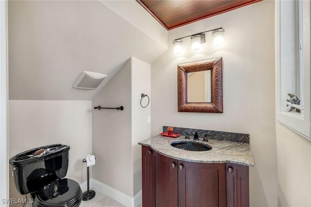 half bath featuring vanity, lofted ceiling, and baseboards