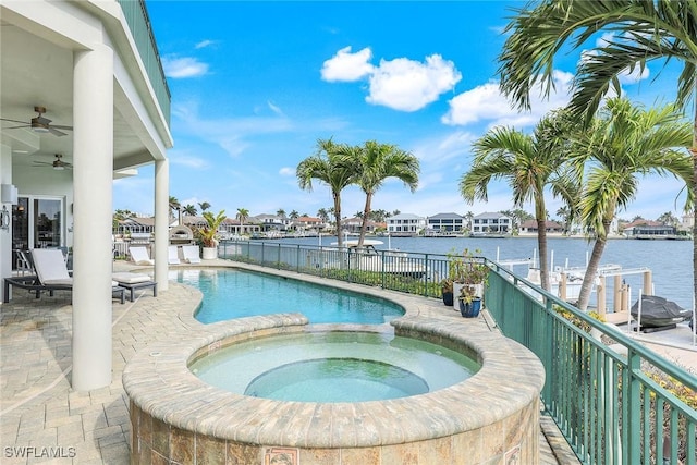 view of pool featuring a pool with connected hot tub, ceiling fan, fence, a water view, and a patio