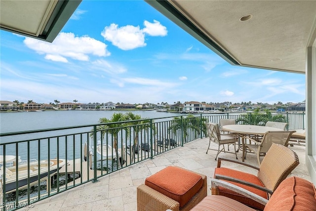 balcony featuring outdoor dining space and a water view