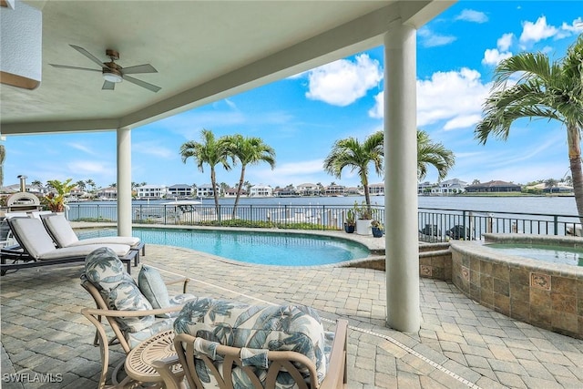 view of pool with a water view, a ceiling fan, fence, an in ground hot tub, and a patio area