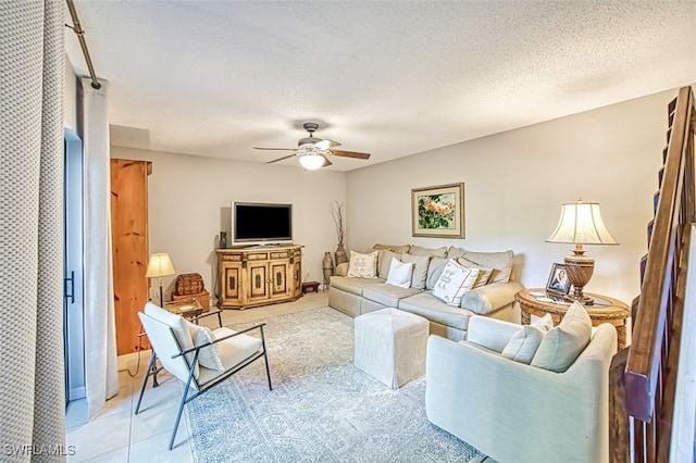 living room with ceiling fan, light tile patterned flooring, and a textured ceiling