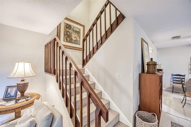 staircase featuring tile patterned flooring, baseboards, and visible vents